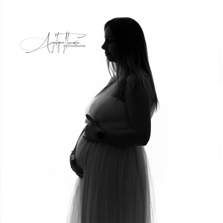 Grossesse Silhouette d'une femme enceinte, en robe légère, se tenant le ventre.